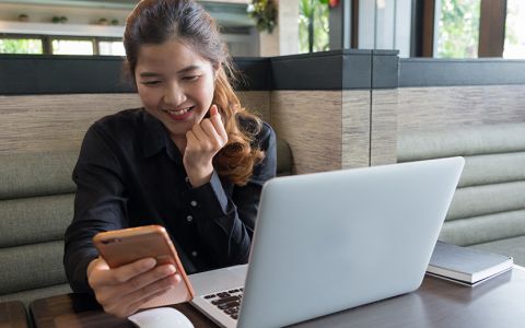 Woman working with cell phone and laptop